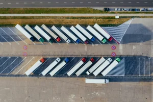 Aerial view of a truck parking lot with multiple semi-trucks lined up in designated spaces. Transportvibe